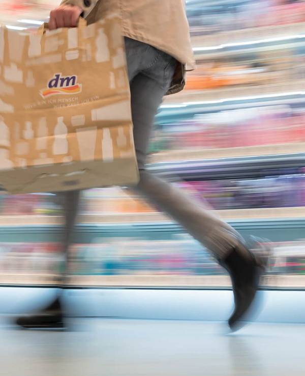 Auf dem Symbolfoto (aufgenommen am 11. November 2021) sieht man eine Frau mit dm-Tragetasche durch das Geschäft gehen.
