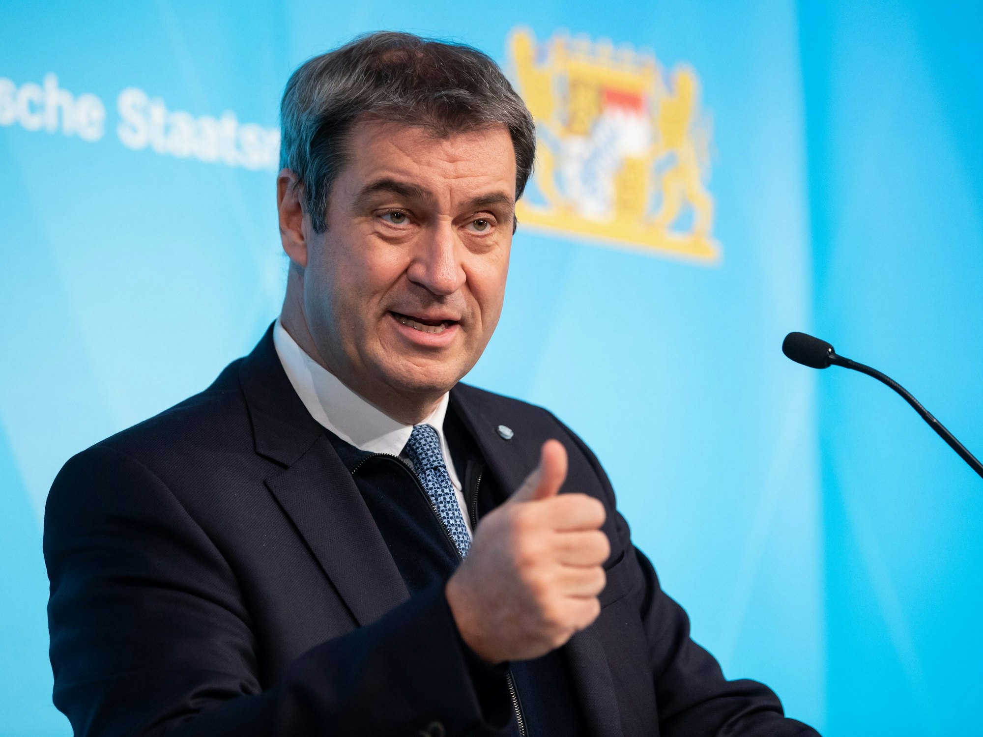 Markus Söder steht auf einem Podium und spricht in ein Mikrofon.