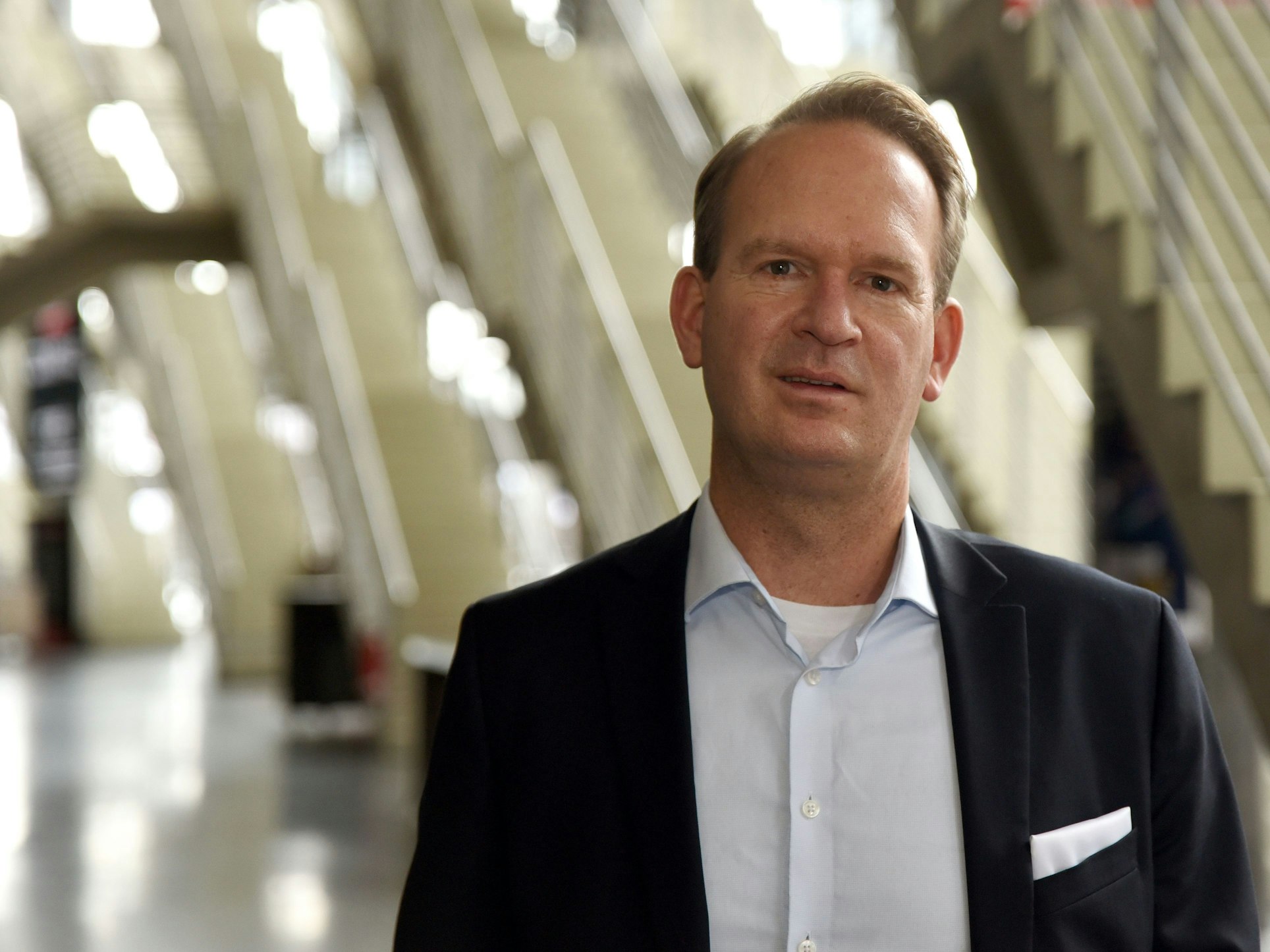 Stefan Löcher, Chef der Lanxess-Arena in Köln, schaut mit einem leichten Grinsen in die Kamera.