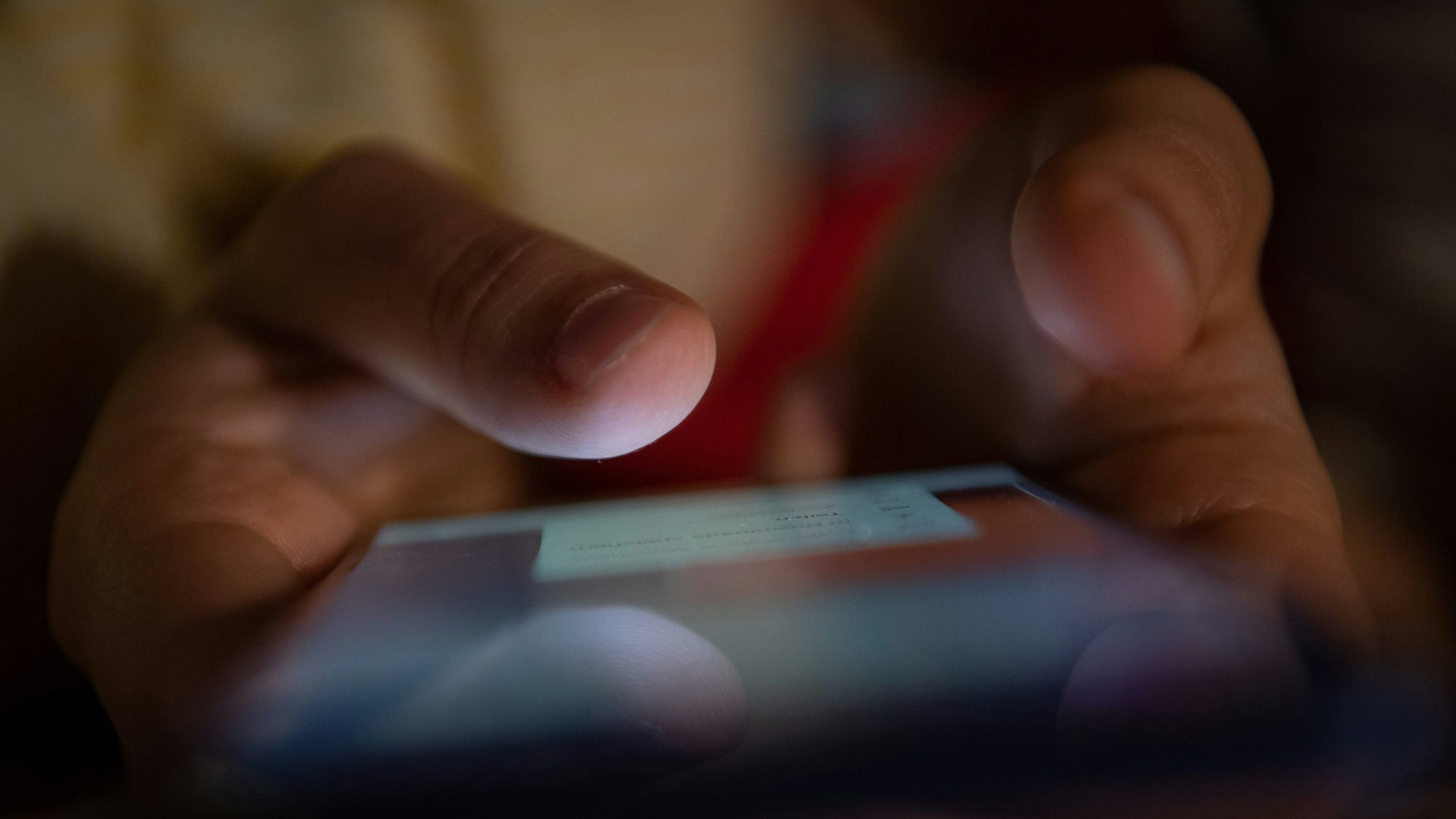 Ein Smartphone wird gehalten und mit zwei Fingern bedient.