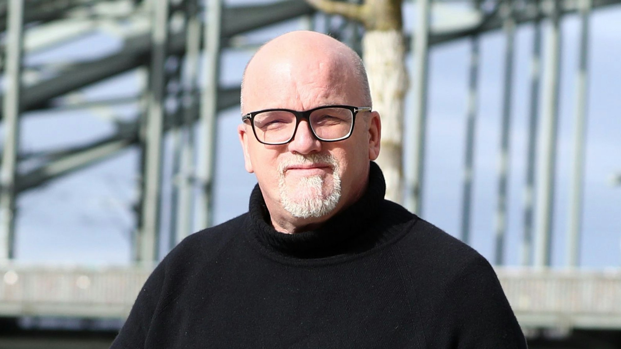 DJ Ötzi läuft am Rhein entlang und blickt in die Kamera.