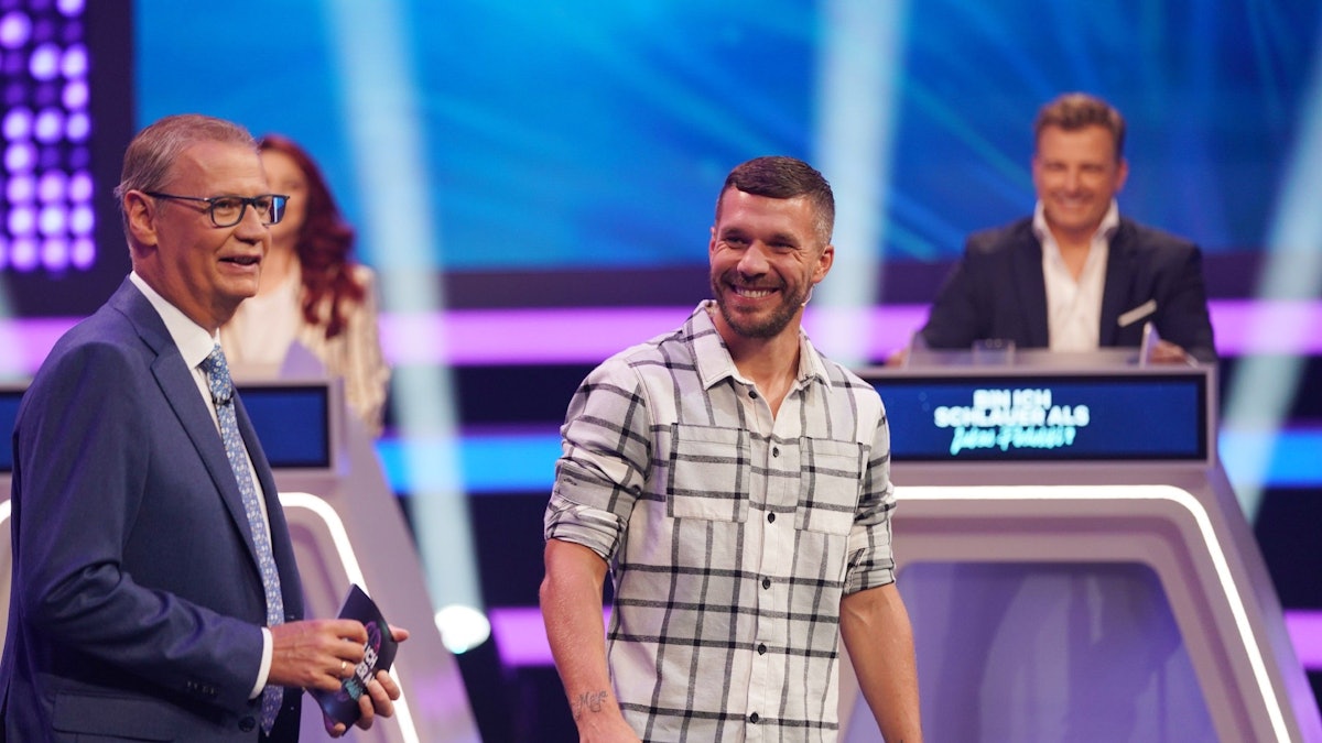 Moderator Günther Jauch und Lukas Podolski stehen in der RTL-Show „Bin ich schlauer als Lukas Podolski?“ nebeneinander.
