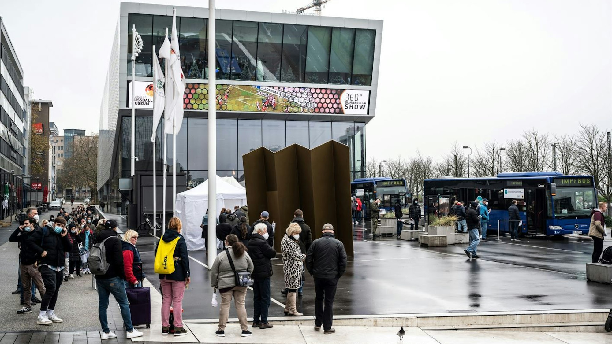 Dortmund: Eine lange Schlange hat sich vor einem mobilen Impfzentrum mit zwei Impfbussen vor dem Deutschen Fußballmuseum gebildet.