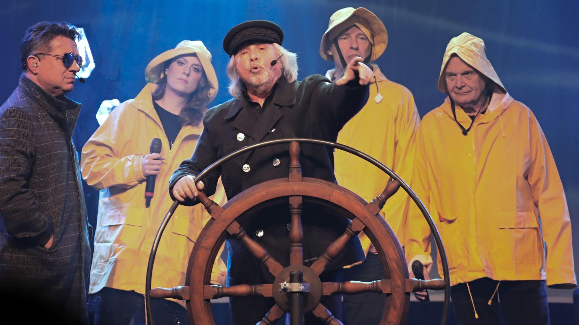 Tommy Engel steht am Steuerrad eines Schiffs, umrahmt von Linus und der Band.