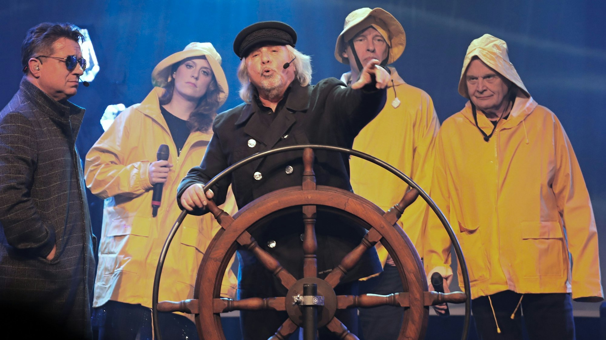 Tommy Engel steht am Steuerrad eines Schiffs, umrahmt von Linus und der Band.