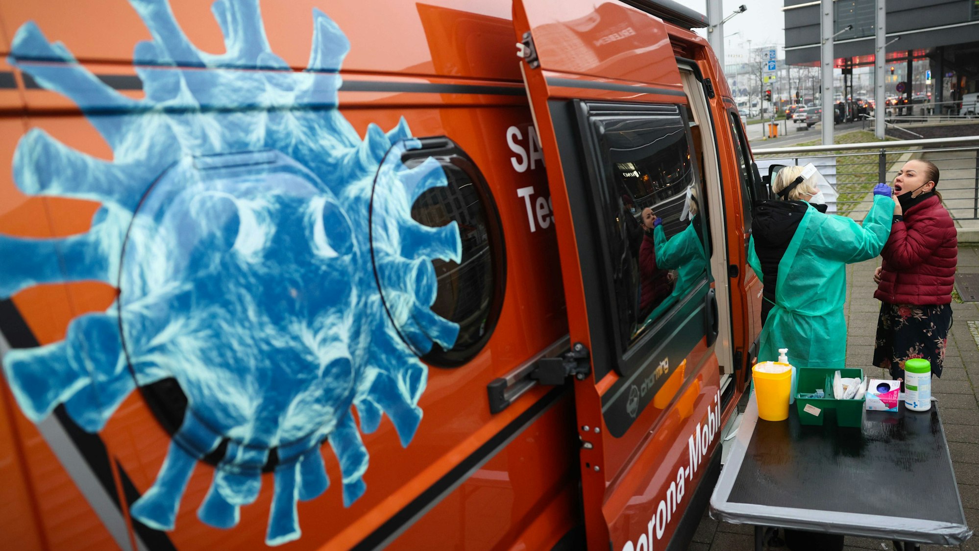 Eine Mitarbeiterin mit Maske und Schutzkleidung macht einen Schnelltest bei einer Frau an einer mobilen Corona-Teststation in der Innenstadt.