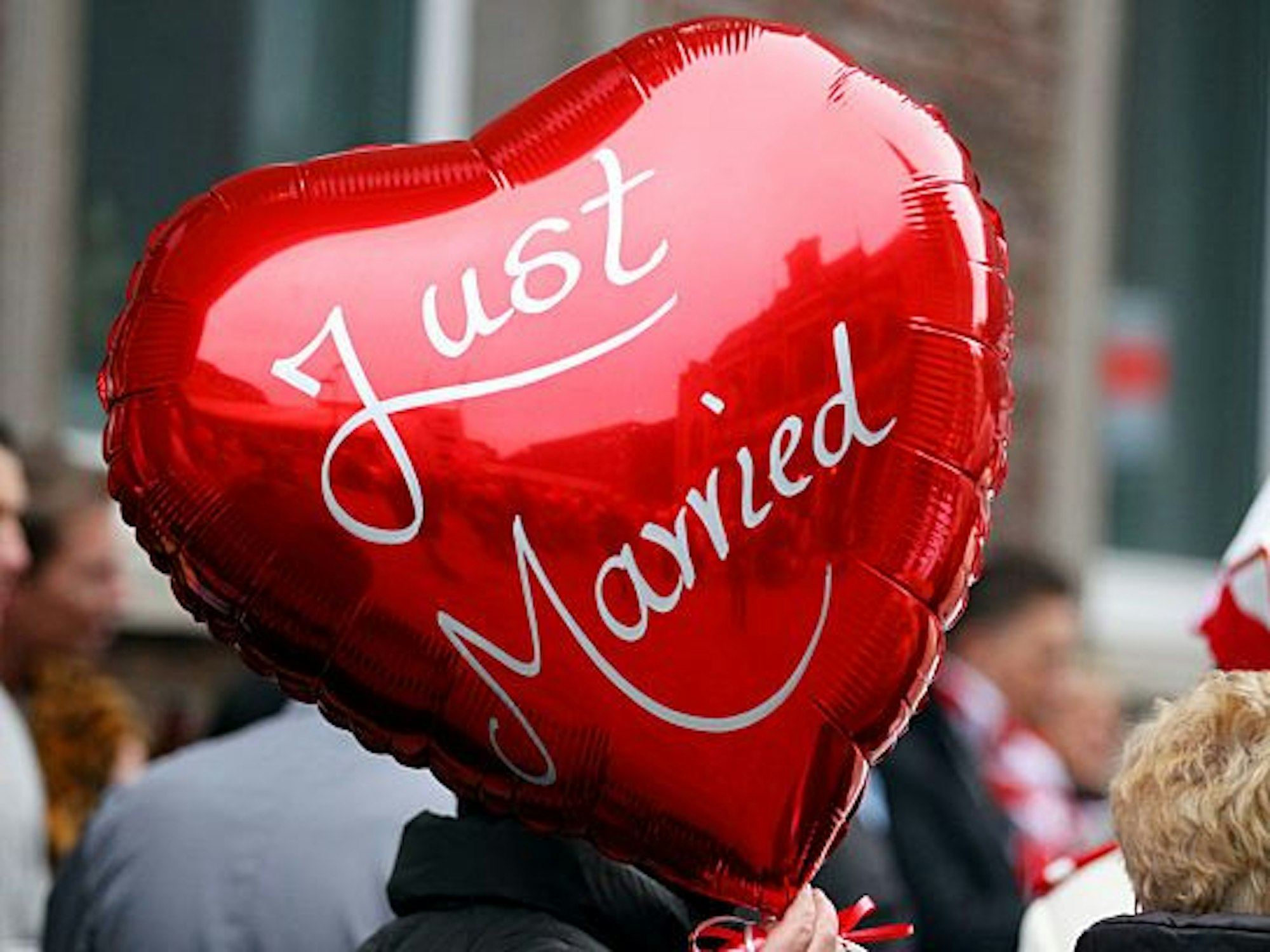 Eine Frau hält einen Ballon mit der Aufschrift „Just Married“ in der Hand.