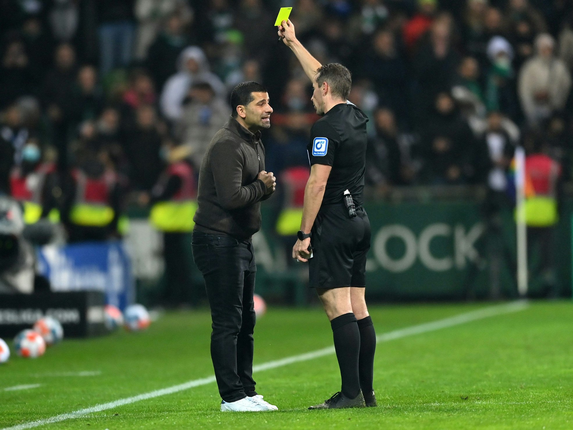 Schiedsrichter Tobias Stieler gibt Schalke-Trainer Dimitrios Grammozis im Topspiel der 2. Bundesliga in Bremen Gelb wegen Meckerns