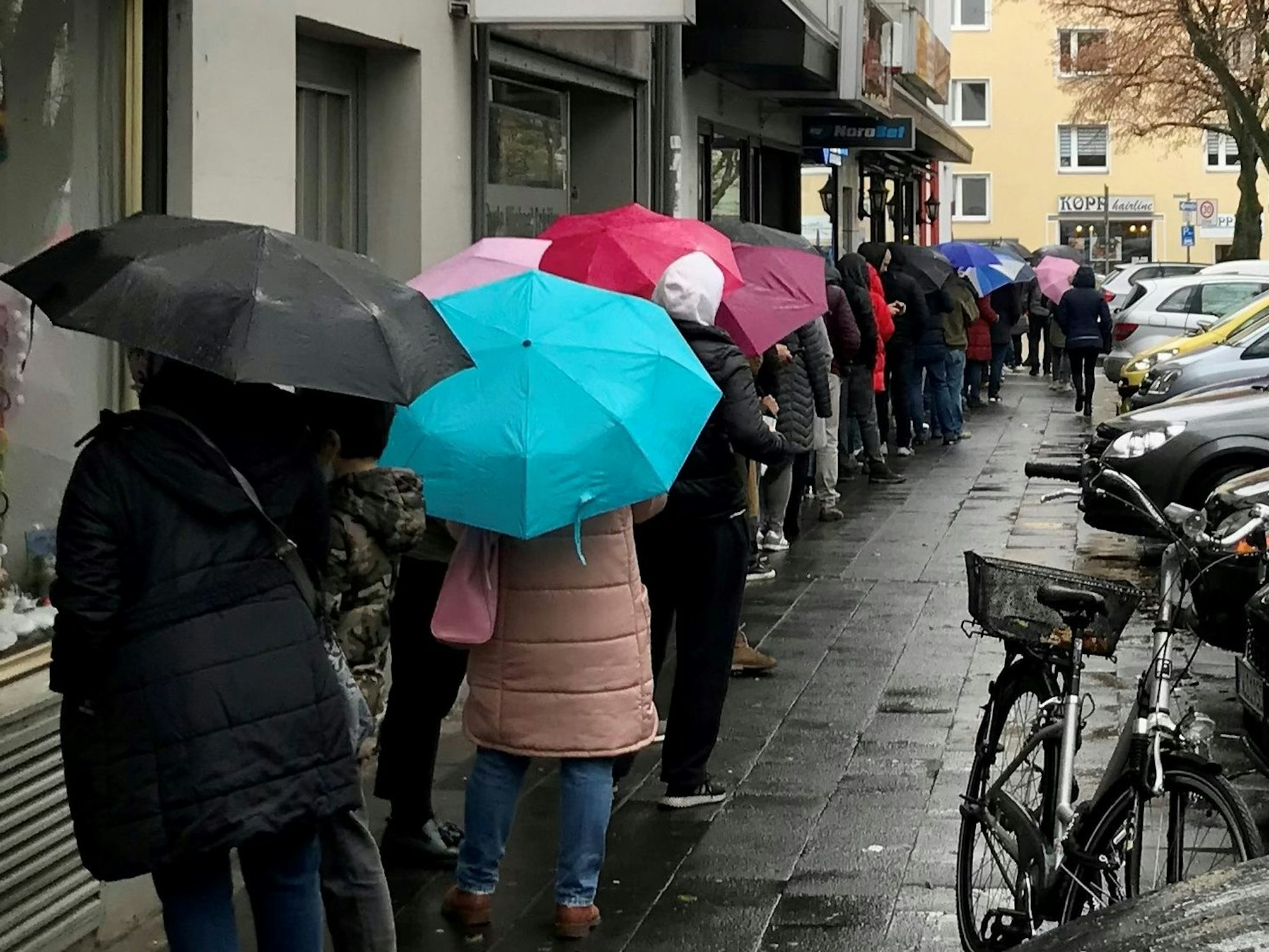 Menschen stehen im Regen Schlange.