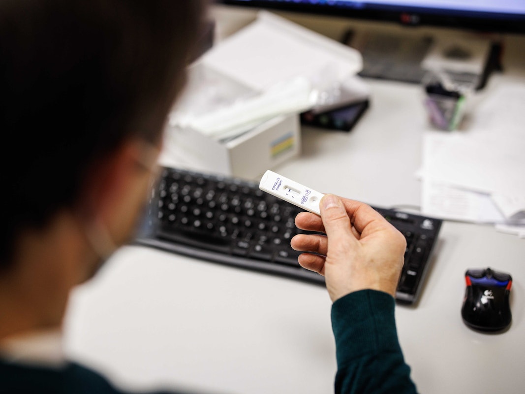Ein Mitarbeiter blickt in einem Produktionsgebäude der Bäckerei- und Konditoreikette Traublinger auf das Testergebnis für einen Corona-Schnelltest eines anderen Mitarbeiters.