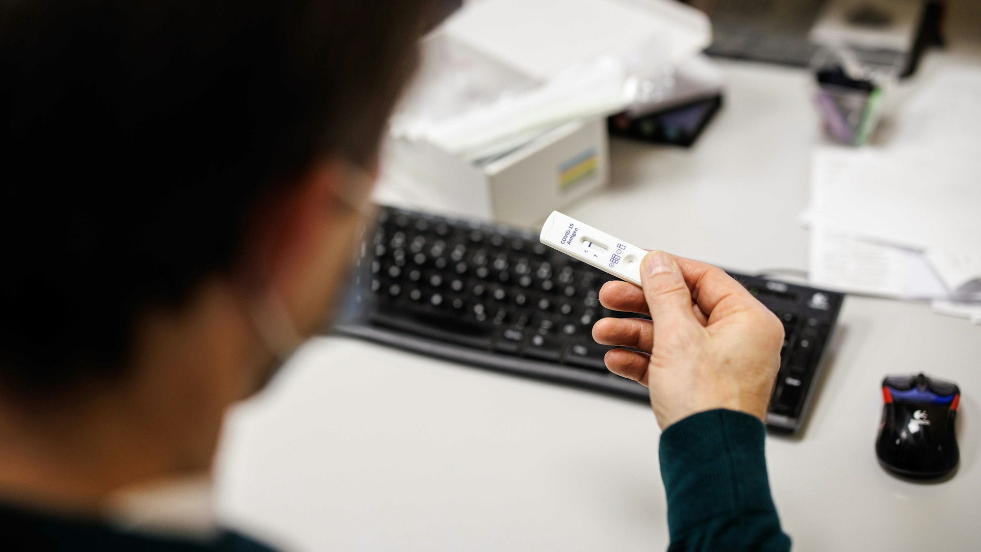 Ein Mitarbeiter blickt in einem Produktionsgebäude der Bäckerei- und Konditoreikette Traublinger auf das Testergebnis für einen Corona-Schnelltest eines anderen Mitarbeiters.