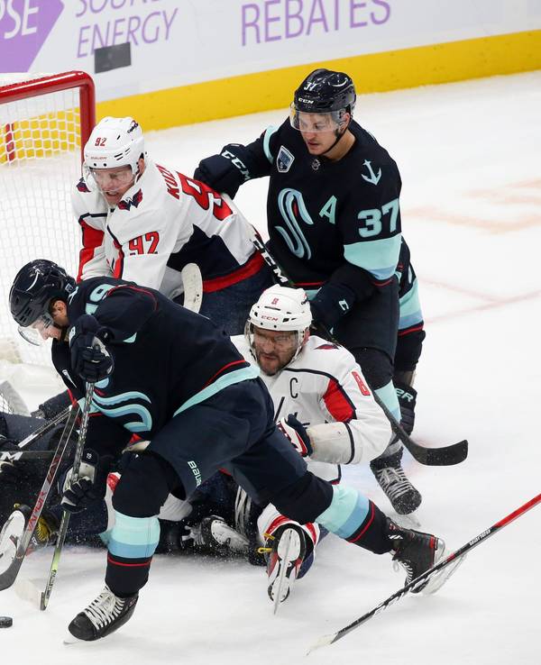 Philipp Grubauer liegt in seinem Tor, weitere Mit- und Gegenspieler tummeln sich um sein Gehäuse. Ein Verteidiger ist im Begriff, den Puck wegzuschlagen.