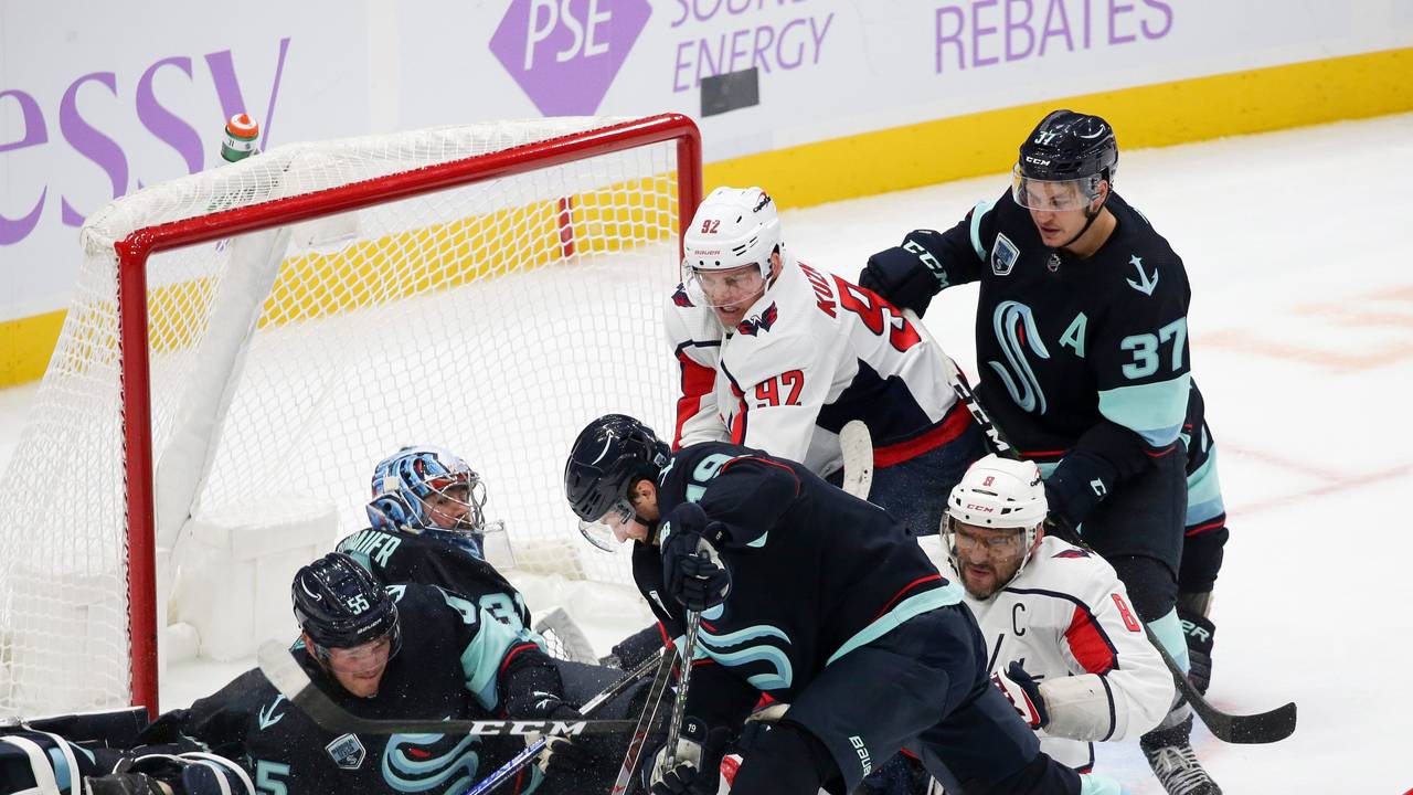 Philipp Grubauer liegt in seinem Tor, weitere Mit- und Gegenspieler tummeln sich um sein Gehäuse. Ein Verteidiger ist im Begriff, den Puck wegzuschlagen.