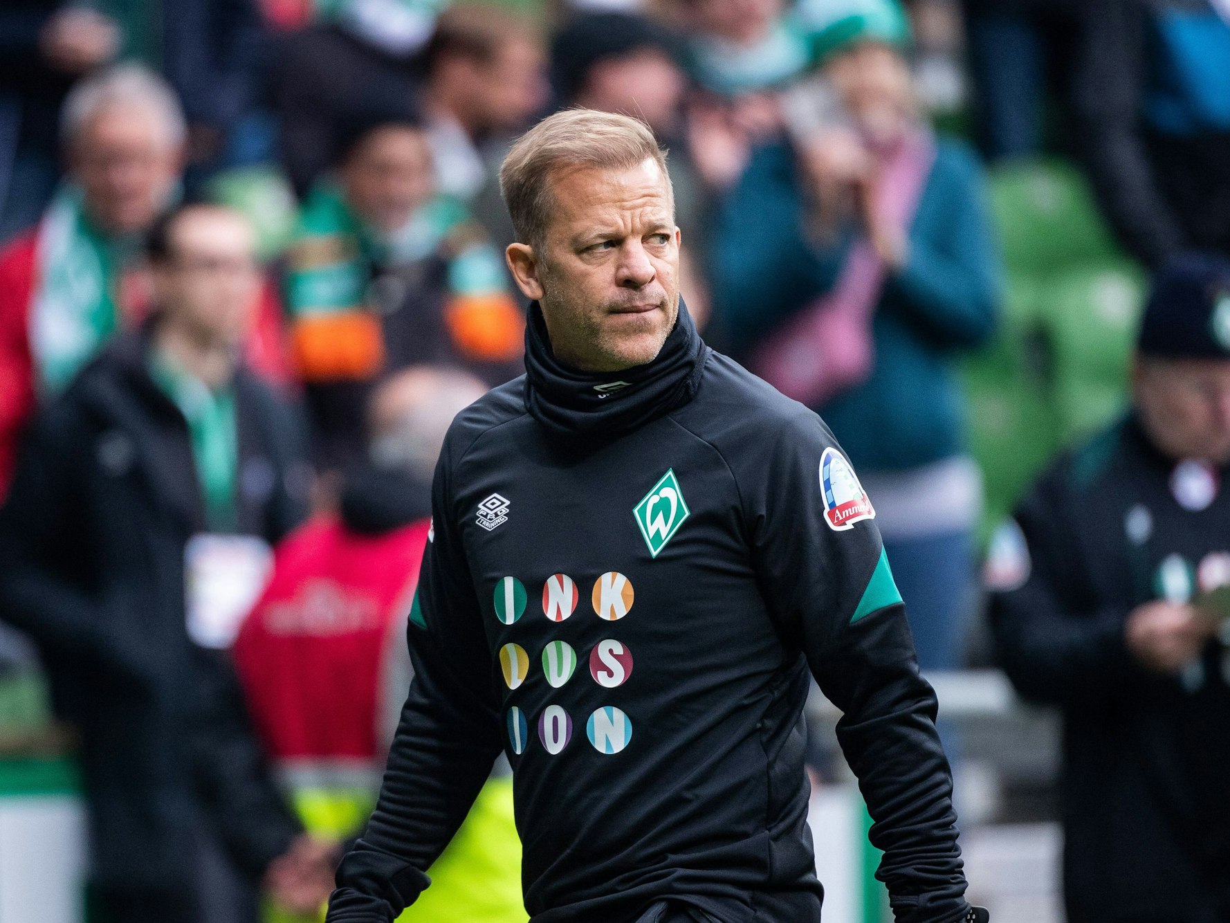 Markus Anfang läuft durch das gefüllte Weserstadion und schaut dabei angespannt.