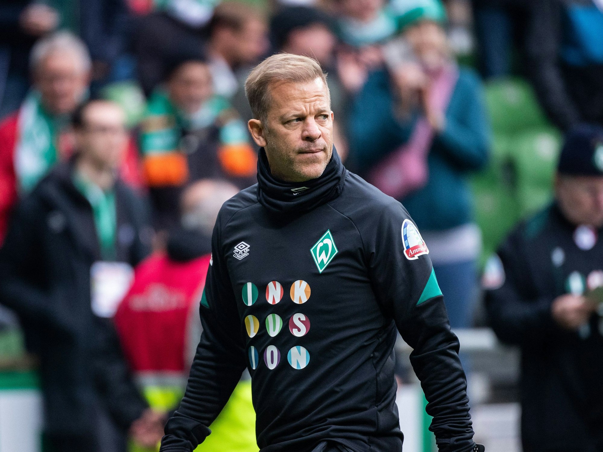 Markus Anfang läuft durch das gefüllte Weserstadion und schaut dabei angespannt.