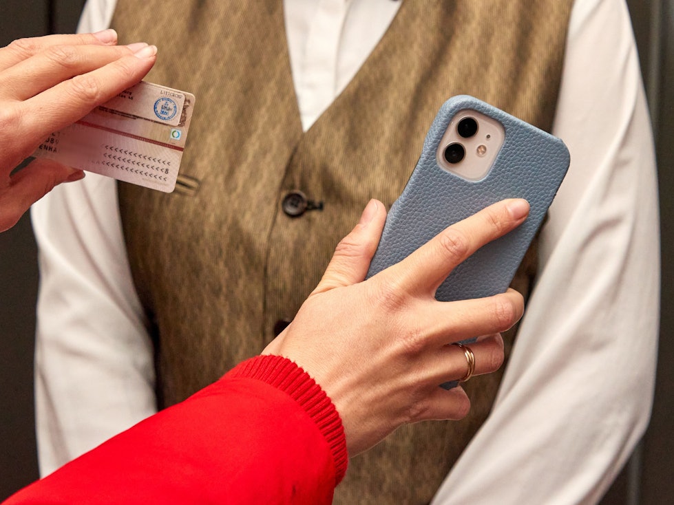 Eine Kinobesucherin (links) hält am 15. November 2021 im Eingang bei der 2G-Kontrolle im Astor Film Lounge HafenCity einer Mitarbeiterin ihren Ausweis und ihr Handy hin.