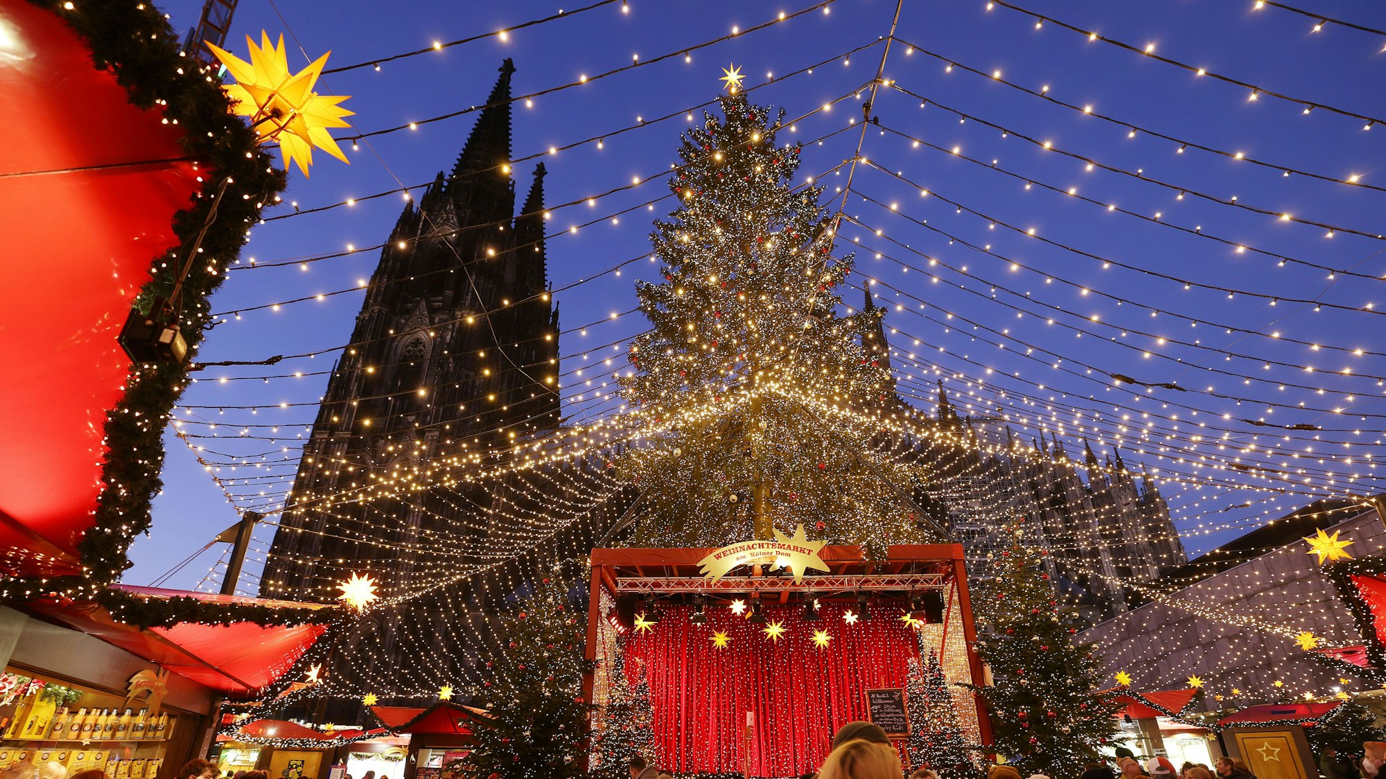 21. November 2021: Besucher gehen über den Weihnachtsmarkt auf dem Roncalliplatz am Dom. Die Weihnachtsmärkte in Köln sind für Besucher unter den 2G-Regeln geöffnet.