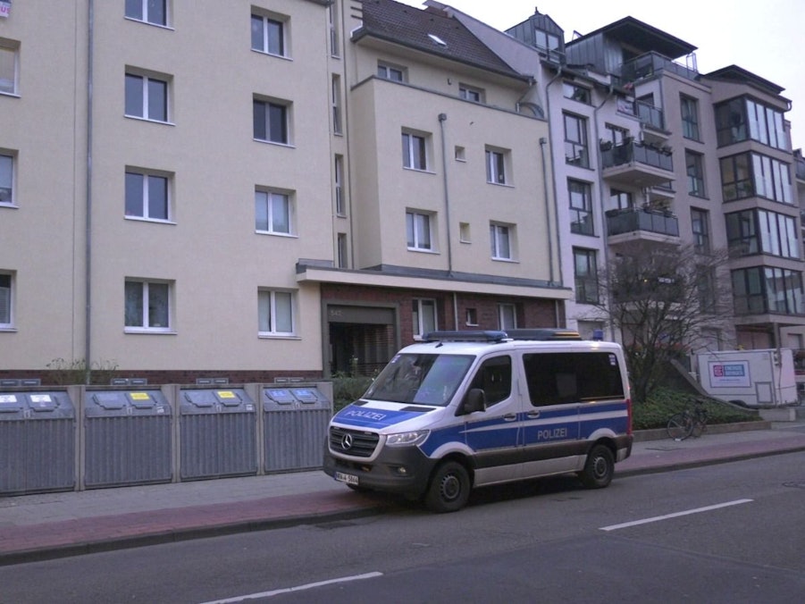 Ein Polizeifahrzeug steht vor einem Mehrfamilienhaus in Köln.