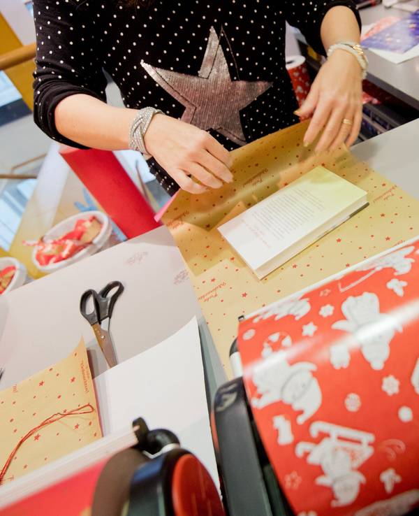 Das Symbolfoto (aufgenommen am 12. Dezember 2018 in Hannover) zeigt eine Buchhändlerin, die ein Buch als Weihnachtsgeschenk verpackt.