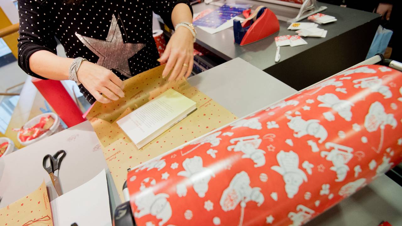 Das Symbolfoto (aufgenommen am 12. Dezember 2018 in Hannover) zeigt eine Buchhändlerin, die ein Buch als Weihnachtsgeschenk verpackt.