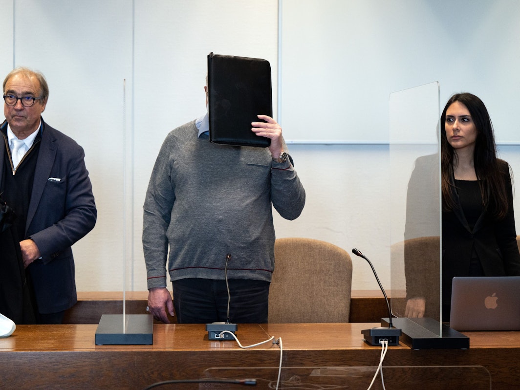 Der angeklagte katholische Priester hält sich im Gerichtssaal eine Mappe vor das Gesicht.