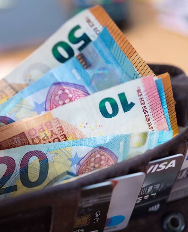 Eine Frau hält eine Geldbörse mit zahlreichen Banknoten und Bankkarten in der Hand. Zu: Wie Sie im Jahr richtig viel Geld sparen können.