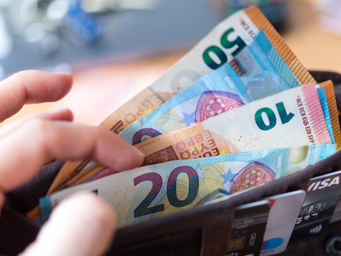 Eine Frau hält eine Geldbörse mit zahlreichen Banknoten und Bankkarten in der Hand. Zu: Wie Sie im Jahr richtig viel Geld sparen können.