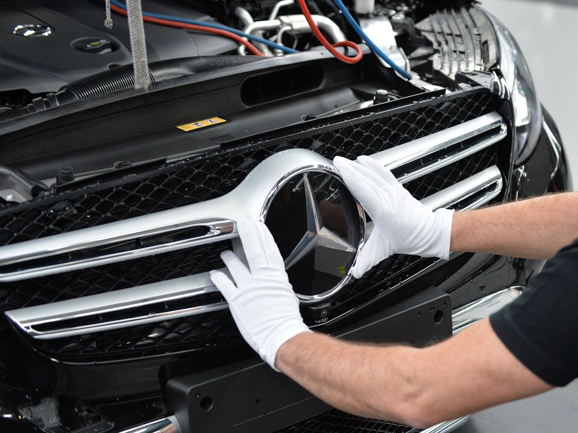 Mercedes-Benz ruft acht Modelle zurück. Dieses undatierte Symbolfoto zeigt einen Arbeiter, der einen Mercedes-Stern am Fahrzeug montiert.