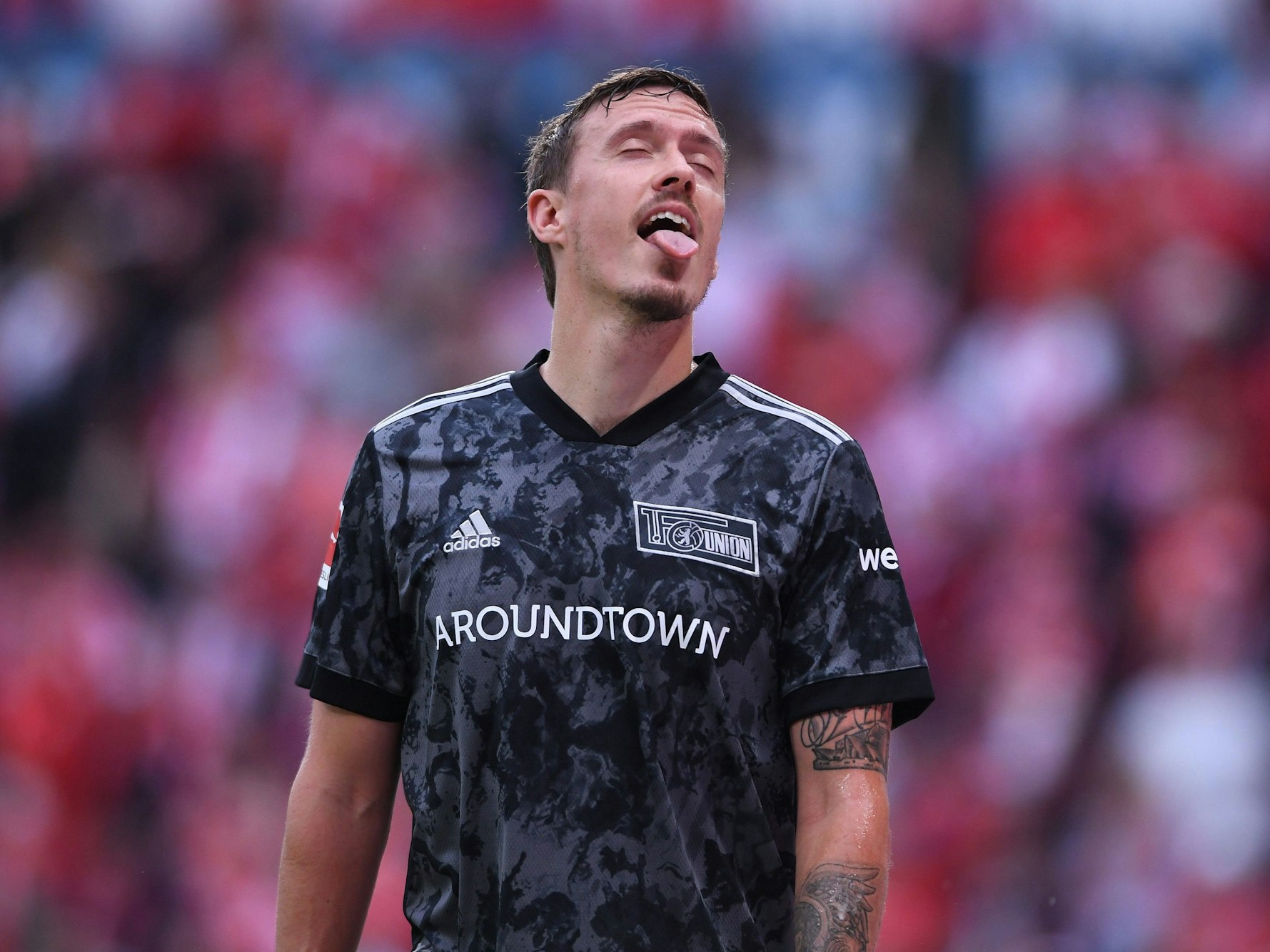 Max Kruse streckt die Zunge nach dem Bier aus, das die Zuschauer nach ihm schmeißen.