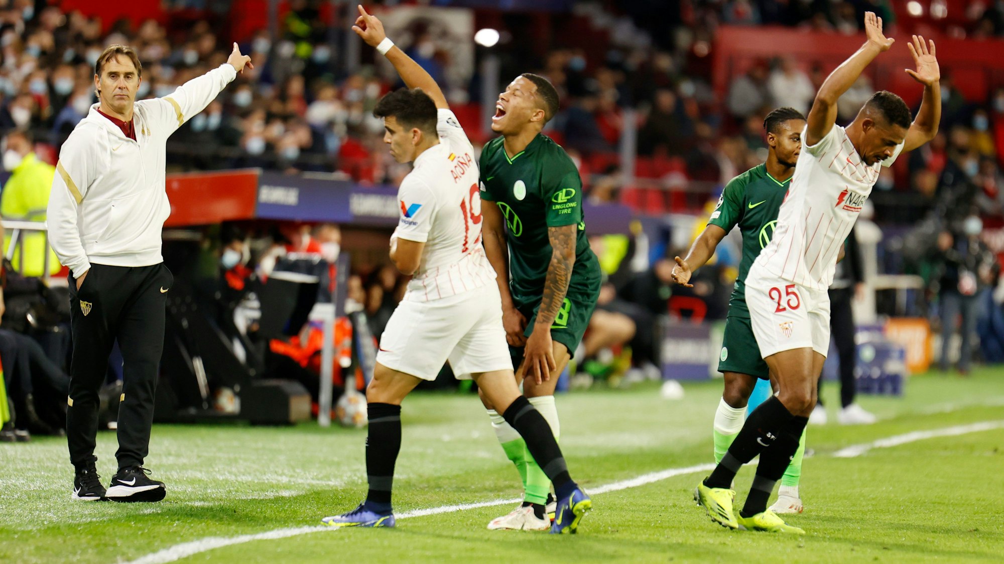 Sevillas Trainer Julen Lopetegui (l) gestikuliert an der Seitenlinie, Wolfsburgs Lukas Nmecha hält sich das Knie.