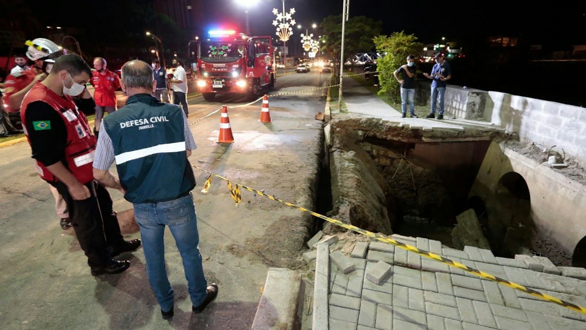 Vertreter des Zivilschutzes, der Feuerwehr und der Polizei stehen am 23. November 2021 an der Unfallstelle in Joinville. Bei einer Eröffnungsveranstaltung der Weihnachtssaison im Süden Brasiliens ist eine zu einer Bucht hin gelegene Promenade eingebrochen – mehr als 30 Menschen fielen in das darunter verlaufende Kanalsystem.