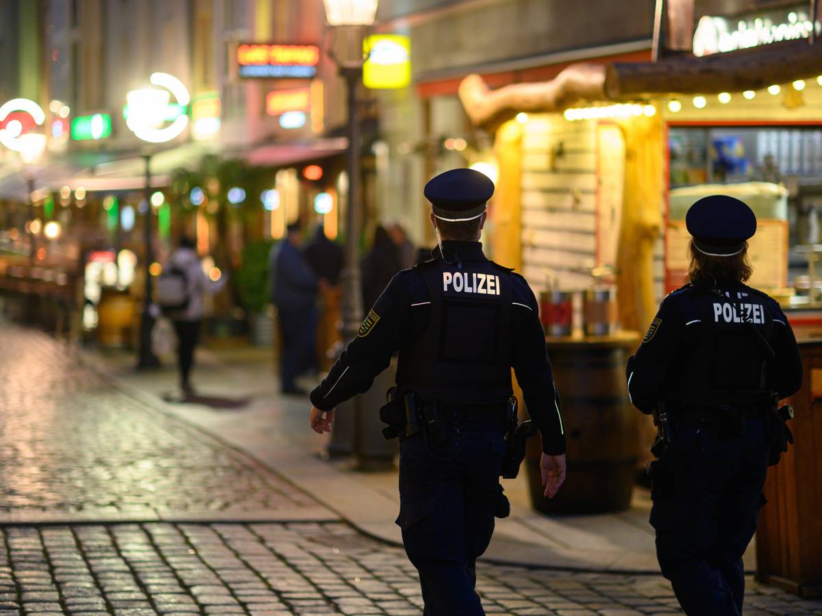 Polizisten gehen an Restaurants entlang.