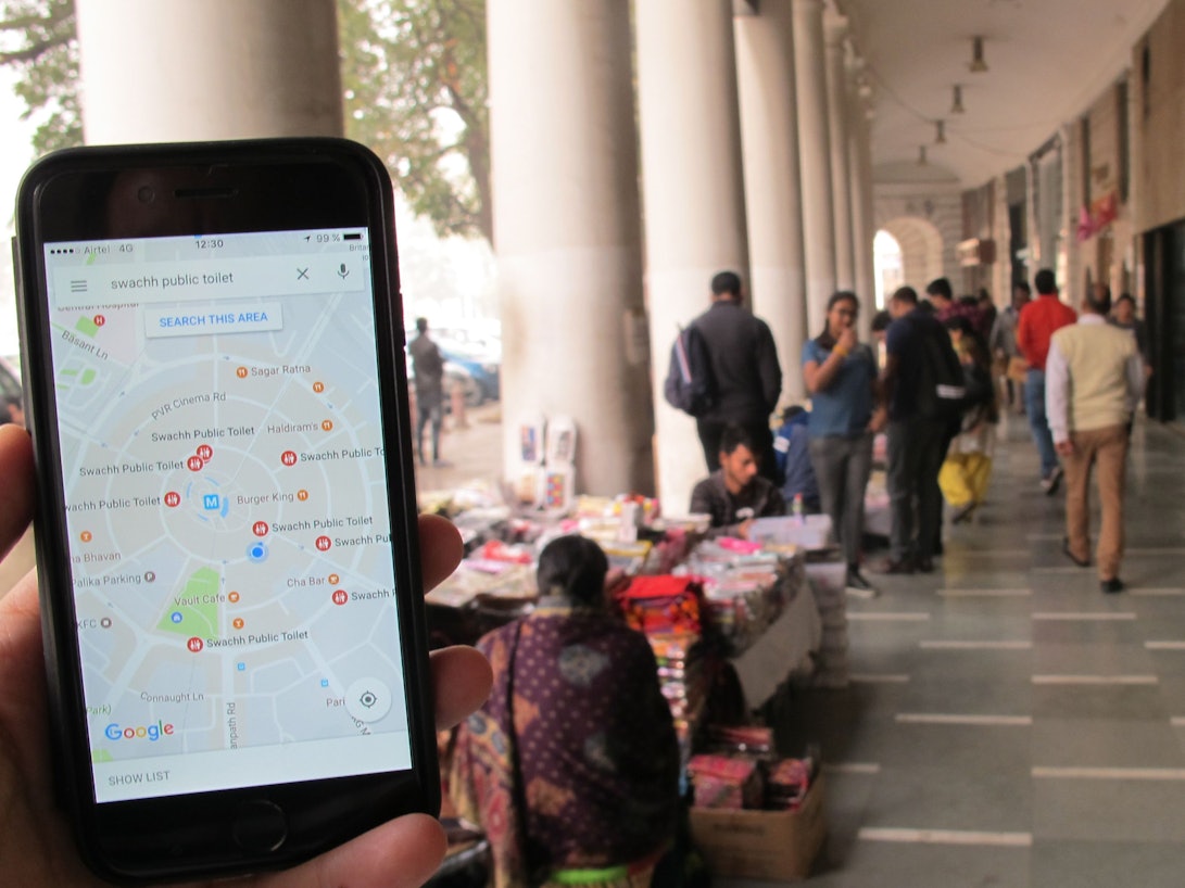 Das Symbolfoto (aufgenommen am 23. Dezember 2016 in Neu Delhi) zeigt ein Handy mit geöffnetem Google Maps, im Hintergrund sieht man den Connaught Place.