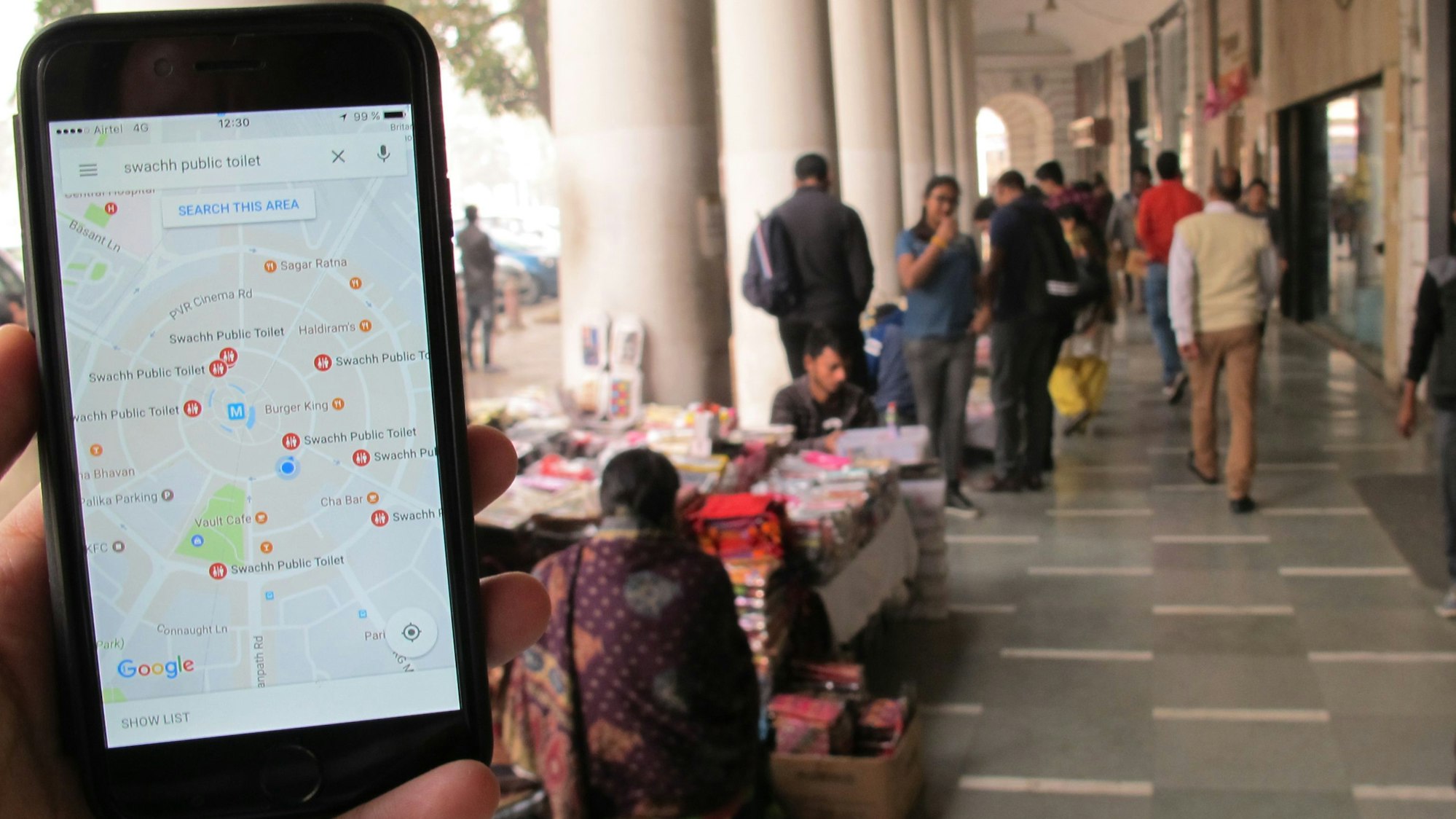 Das Symbolfoto (aufgenommen am 23. Dezember 2016 in Neu Delhi) zeigt ein Handy mit geöffnetem Google Maps, im Hintergrund sieht man den Connaught Place.