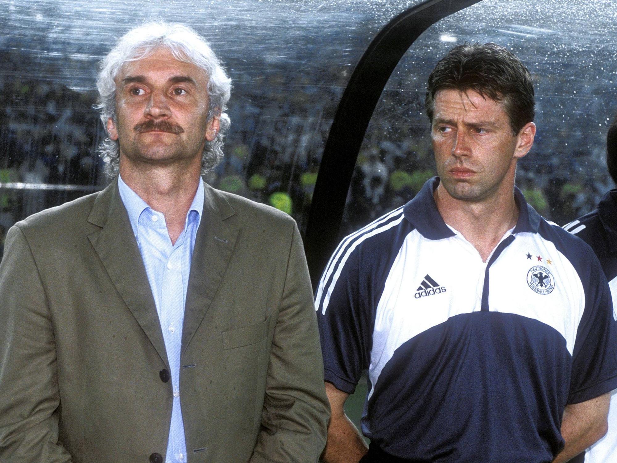 Michael Skibbe steht neben Rudi Völler und hat die Hände auf dem Rücken verschränkt.