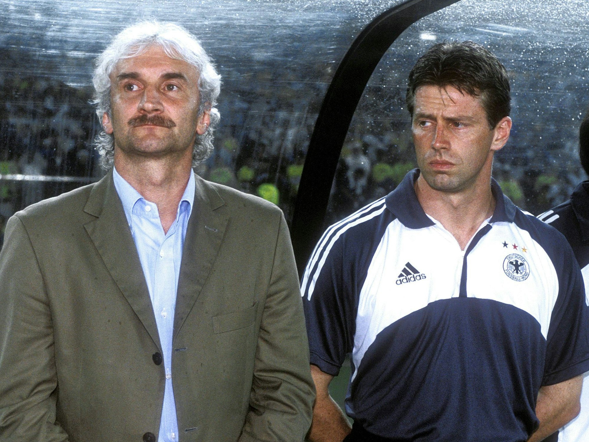 Michael Skibbe steht neben Rudi Völler und hat die Hände auf dem Rücken verschränkt.