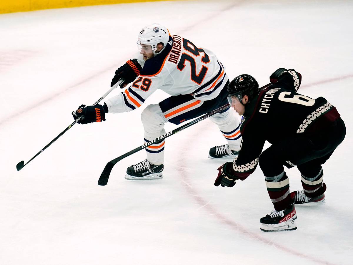 Eishockey-Profi Leon Draisaitl (l.) befindet sich im Sprintduell mit Jakob Chychrun, beide jagen dem Puck nach.