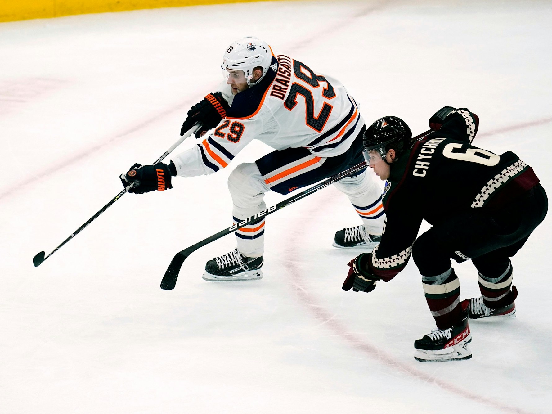 Eishockey-Profi Leon Draisaitl (l.) befindet sich im Sprintduell mit Jakob Chychrun, beide jagen dem Puck nach.