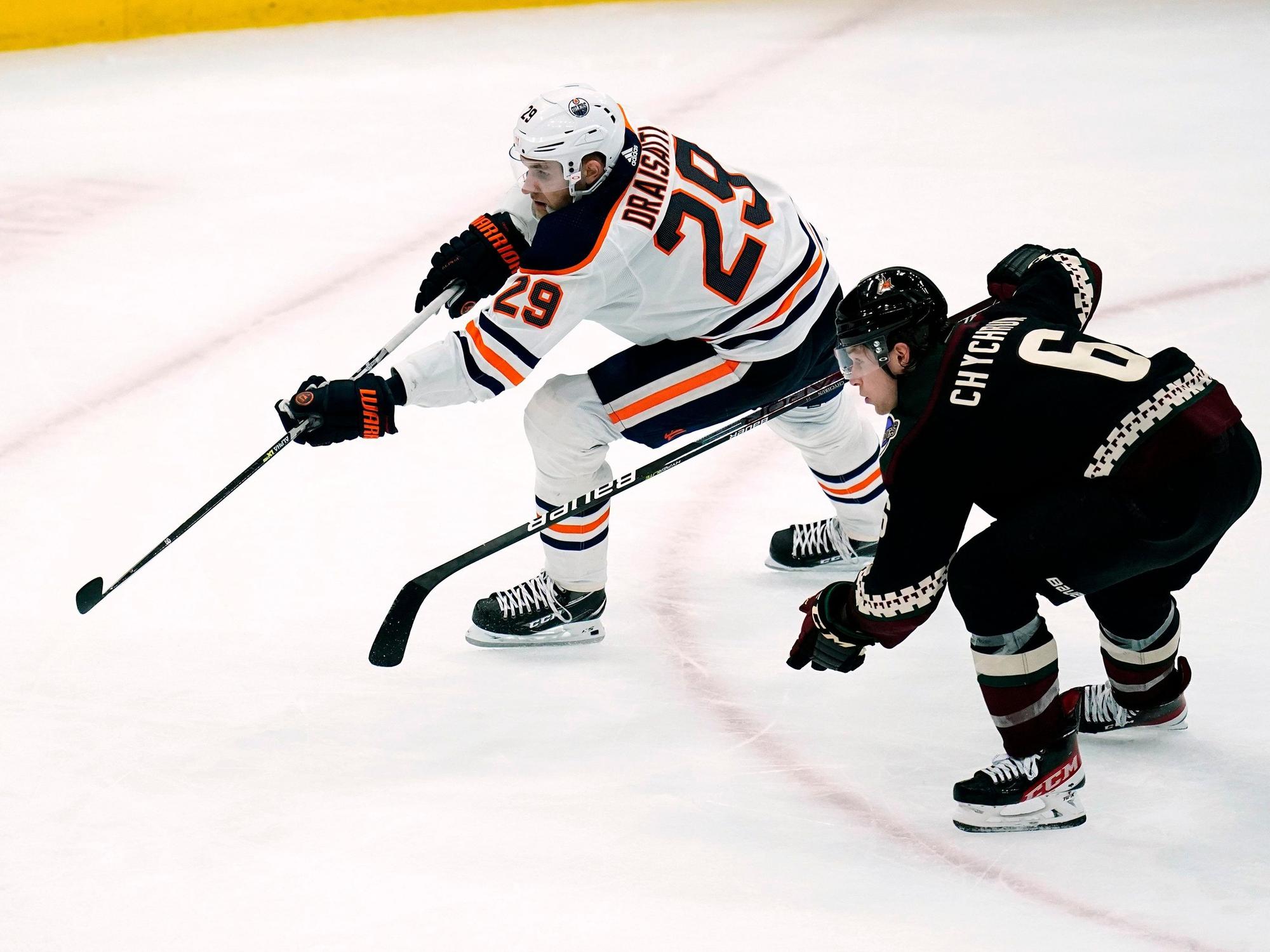 Eishockey-Profi Leon Draisaitl (l.) befindet sich im Sprintduell mit Jakob Chychrun, beide jagen dem Puck nach.