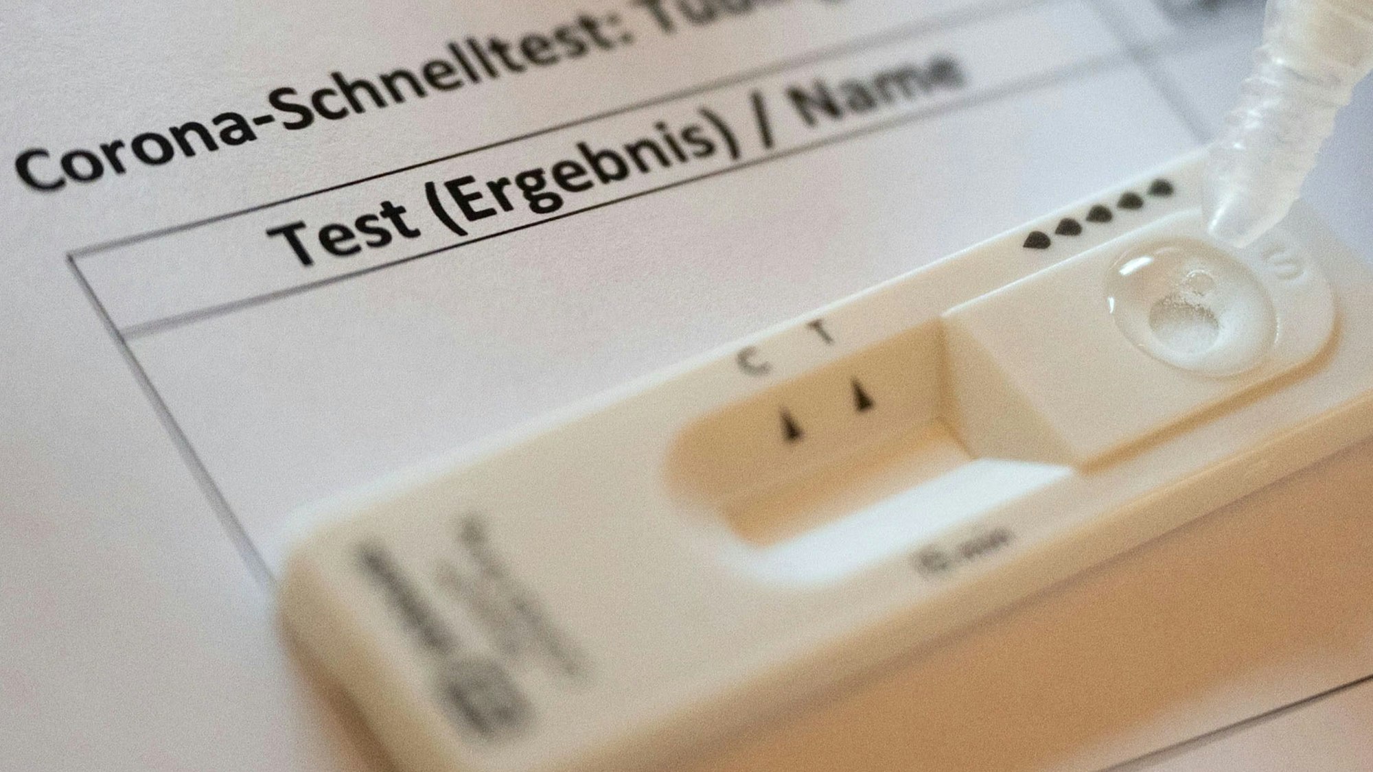 Ein Mitarbeiter einer Corona-Teststation auf dem Marktplatz vor dem Rathaus träufelt Sekretlösung in die Kartusche eines Schnelltests.