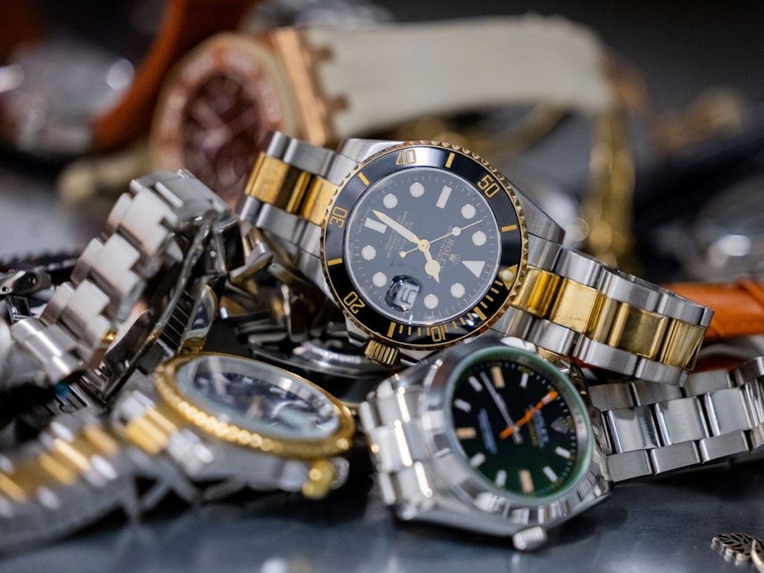 Gefälschte Markenuhren liegen im Hauptzollamt Köln auf einem Regal.