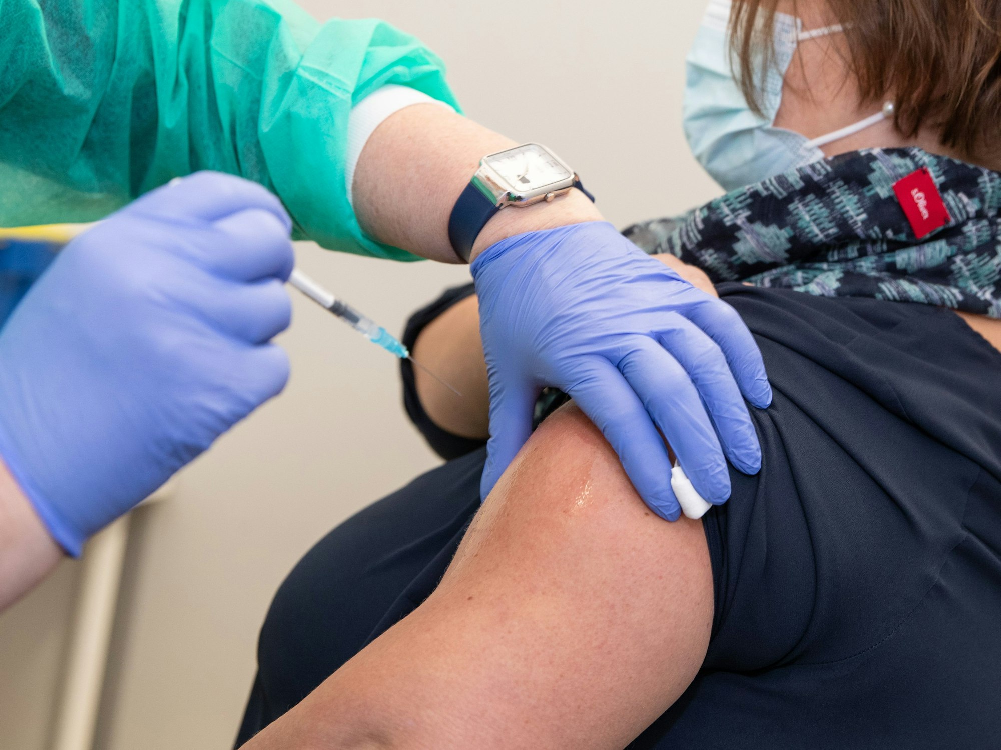 Eine Arzthelferin hält eine Spritze bereit zur Impfung in den Oberarm einer Frau in einem Impfzelt.