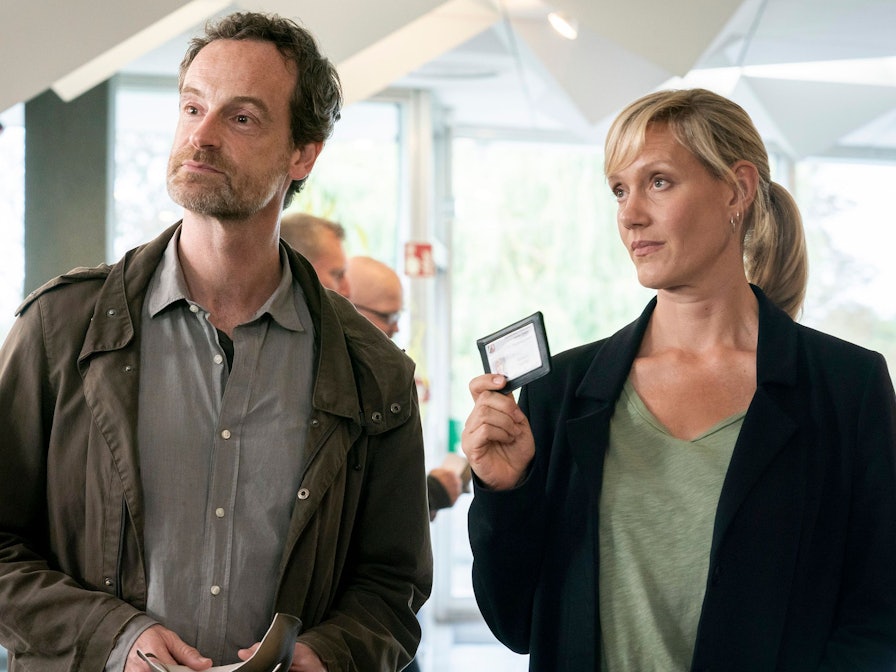 Peter Faber und Martina Bönisch stehen nebeneinander, Bönisch zeigt ihren Dienstausweis.