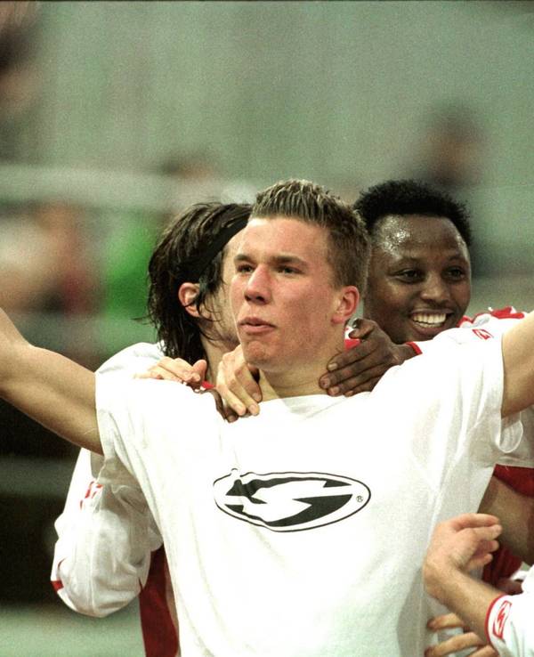 Lukas Podolski breitet beim Jubeln die Arme aus und wird umringt von seinen Mitspielern.