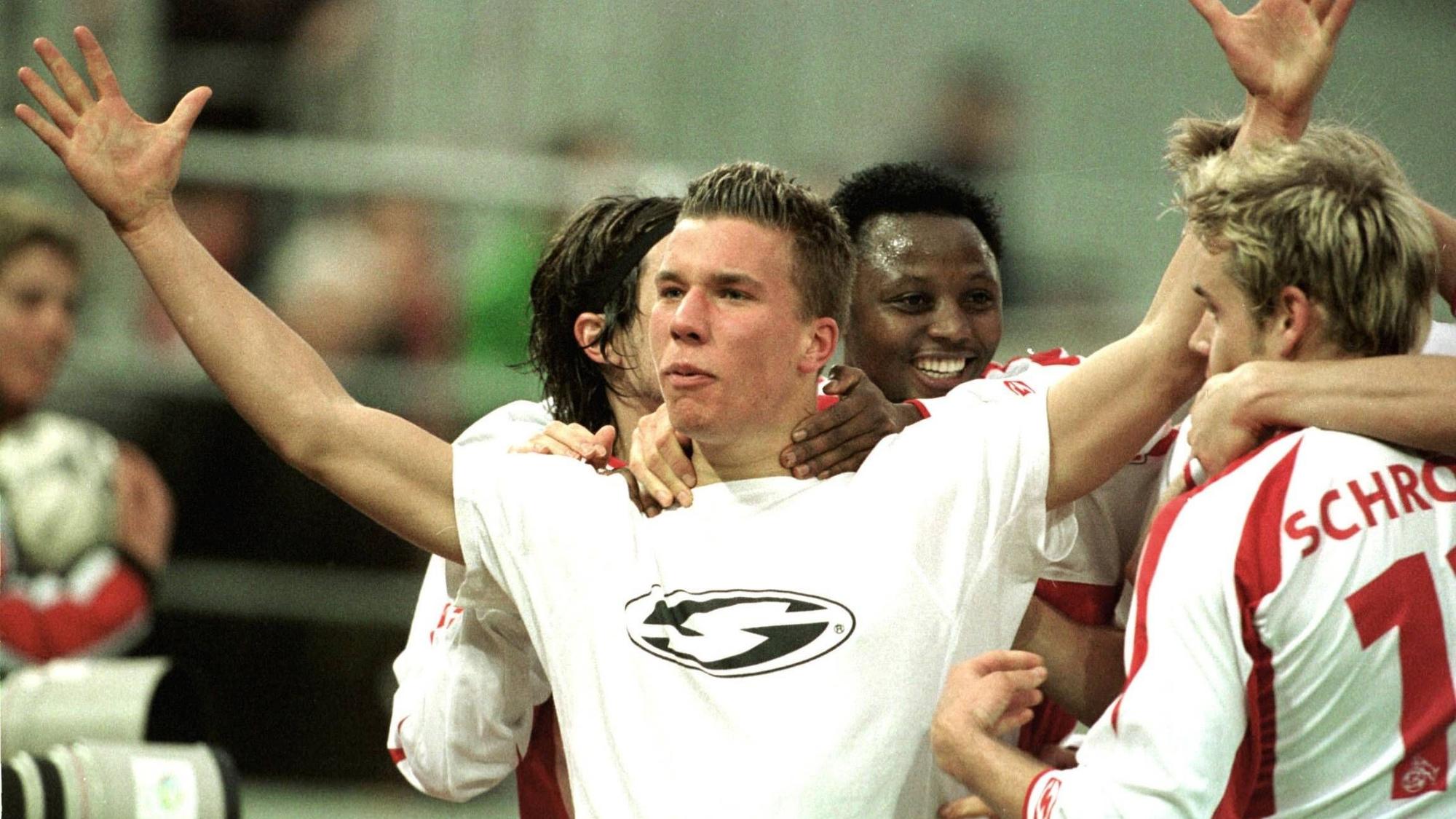 Lukas Podolski breitet beim Jubeln die Arme aus und wird umringt von seinen Mitspielern.