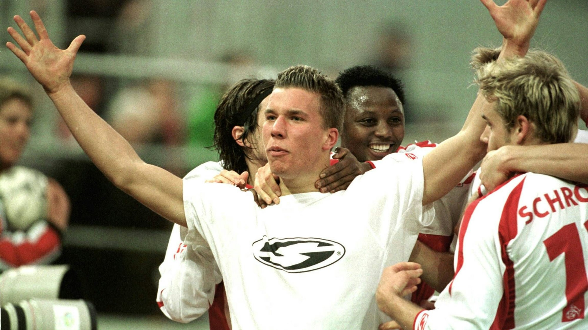 Lukas Podolski breitet beim Jubeln die Arme aus und wird umringt von seinen Mitspielern.