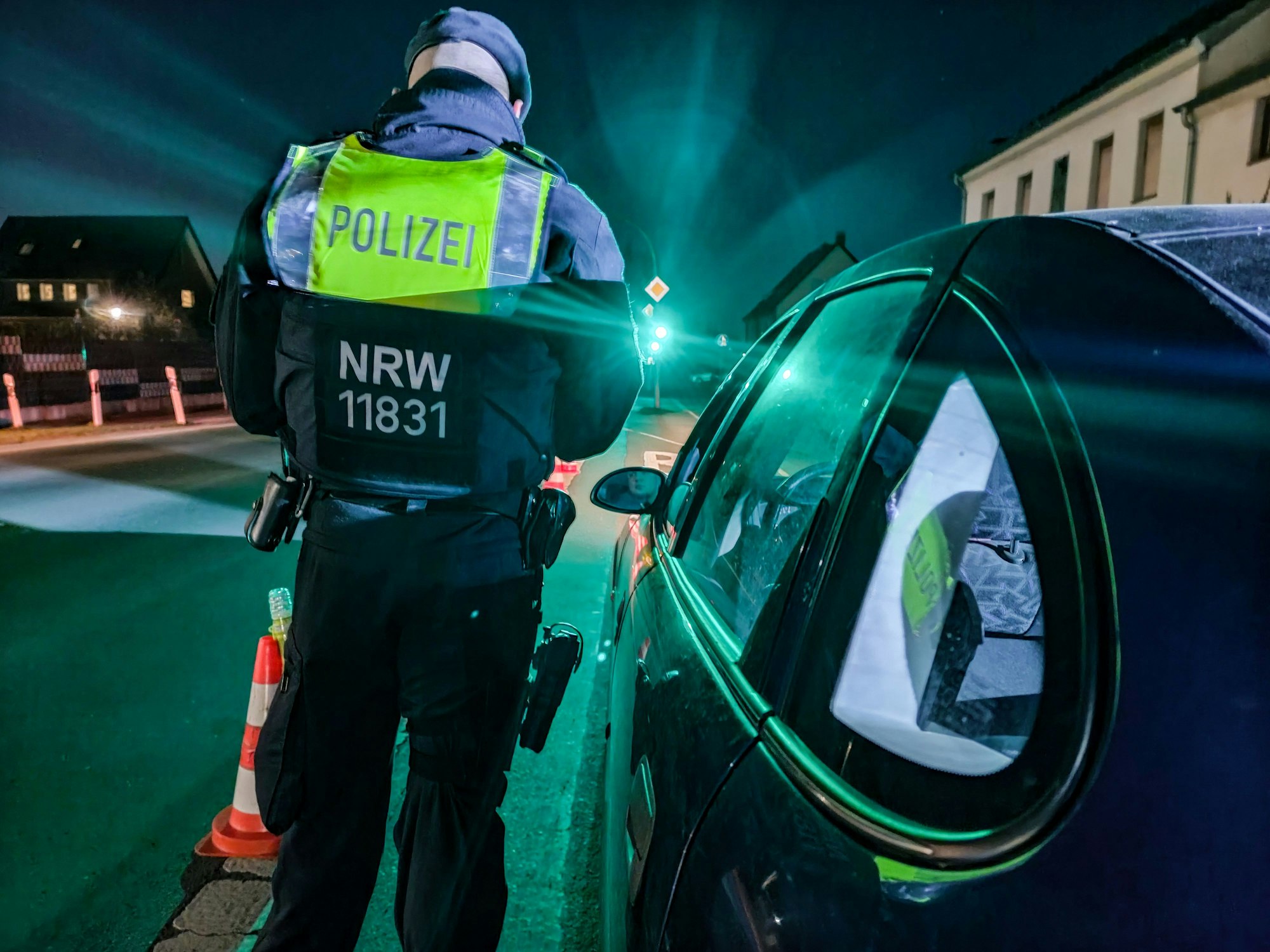 Ein Polizist steht an einem Auto und führt eine Kontrolle durch.