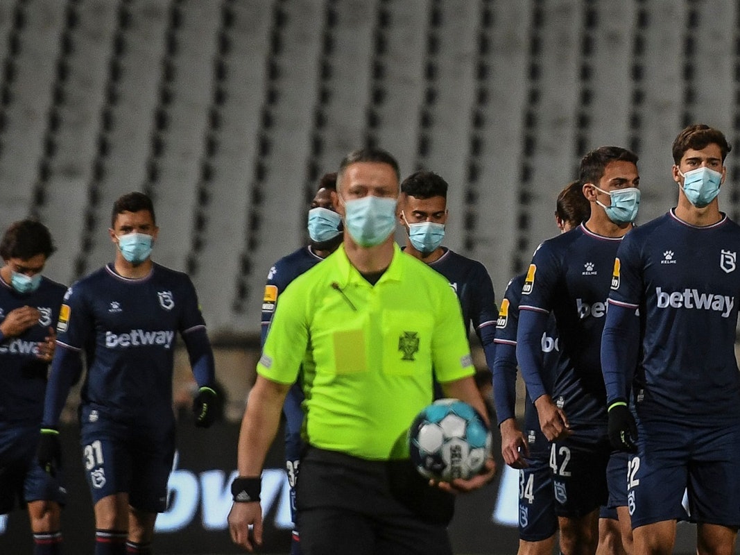 Die Spieler von Belenenses Lissabon und der Schiedsrichter gehen mit Masken auf den Platz.