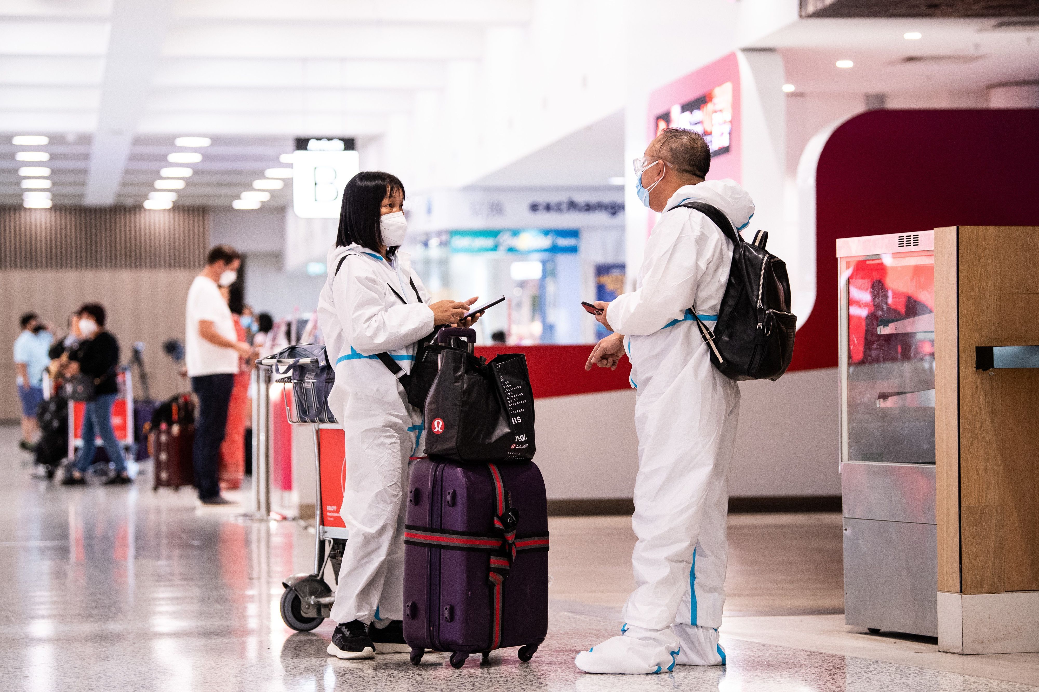 Reisende tragen eine persönliche Schutzausrüstung (PSA) bei ihrer Ankunft am internationalen Flughafen Sydney am 29. November. Die neu entdeckte Omikron-Variante des Coronavirus ist in Australien angekommen. Die WHO stuft das Risiko durch die neue Variante als „sehr hoch“ ein.