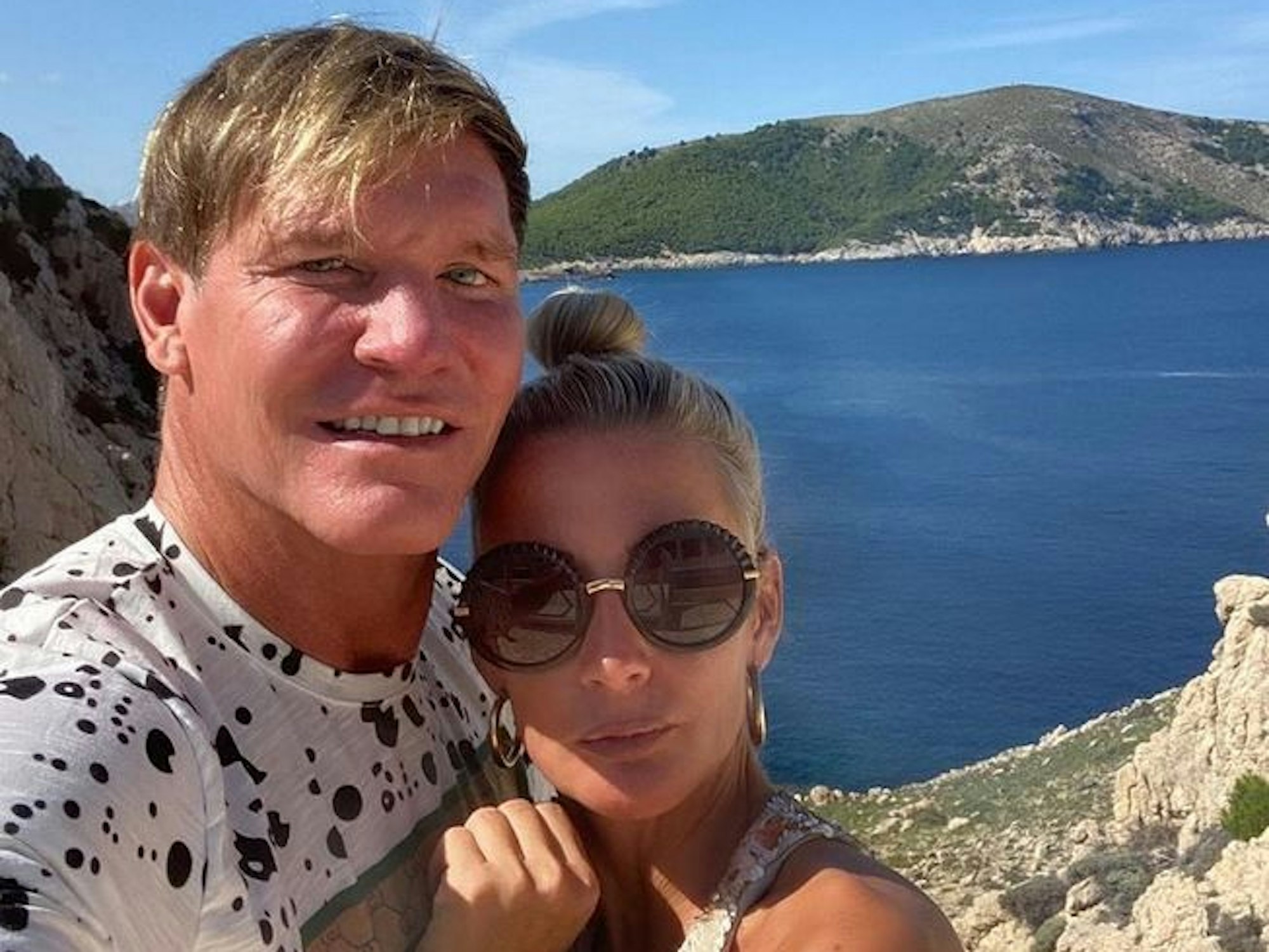 Peggy Jerofke und Steff Jerkel posieren für ein Instagram-Selfie. Im Hintergrund sind eine steile Küste und das offene Meer zu sehen. Peggy Jerofke hat das Foto am 8. Oktober 2021 auf Instagram veröffentlicht.
